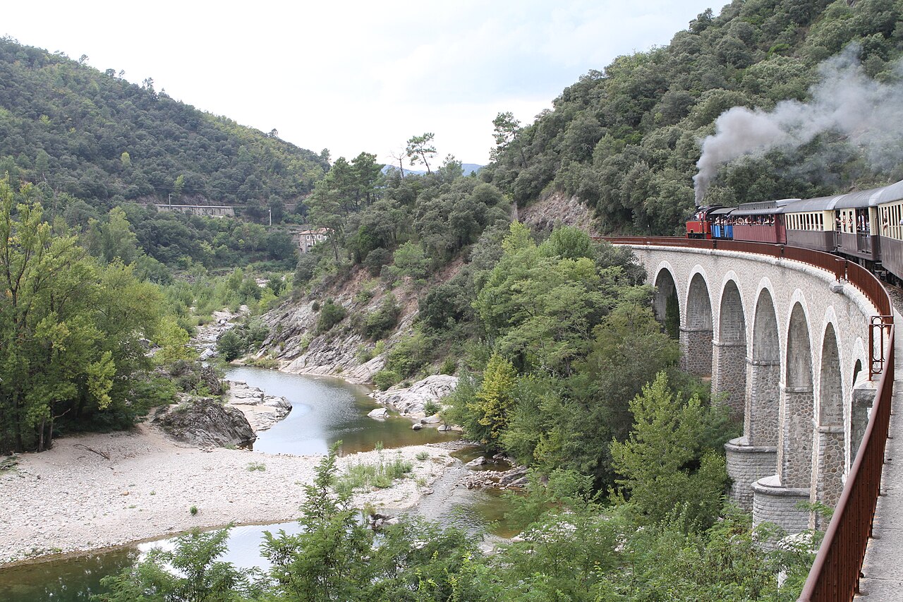 French heritage steam train crossing a stone viaduct over a river gorge